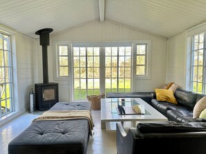 Una habitación acogedora con chimenea, un sofá, una mesita de centro y ventanas amplias.