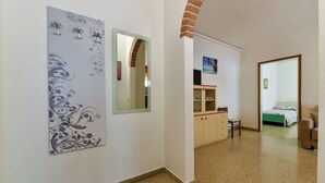 Un couloir avec un miroir, une commode, un lit et une chaise.
