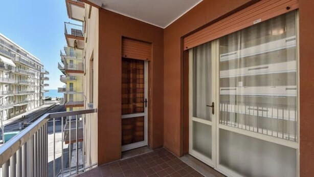 Un balcon offrant une vue sur d’autres immeubles et un ciel dégagé.