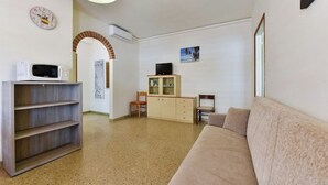 Un salon avec un canapé, un téléviseur, un meuble et un four à micro-ondes.