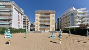Een strandhotel met meerdere verdiepingen, buitenzitplaatsen en een zandstrand.