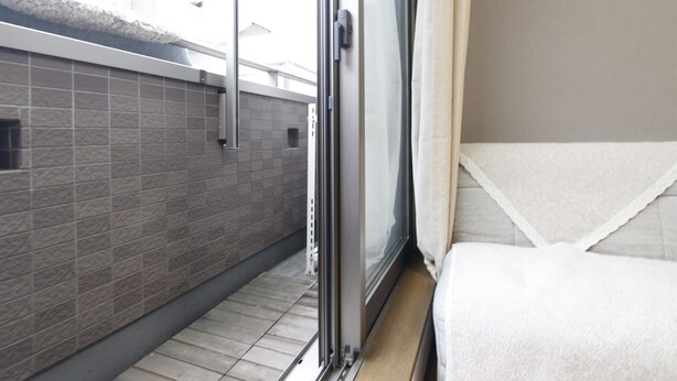 A hotel room with a sliding glass door leading to a balcony, tiled walls, and a bed with a white cover. - 201_Shinjuku Gourmet&Shopping Recently (新宿区)
