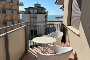 A balcony with a table and chairs, overlooking a body of water and buildings. - Lido di Jesolo, Italy. Entire accommodation (Lido di Jesolo)
