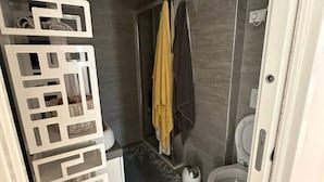Une salle de bain au design moderne, comprenant des toilettes, un espace douche et un porte-serviettes.