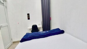 A small, simple room with a bed, a desk, and a chair. - OYO 94046 Tamansari Panoramic Apartment By Aw (Bandung)