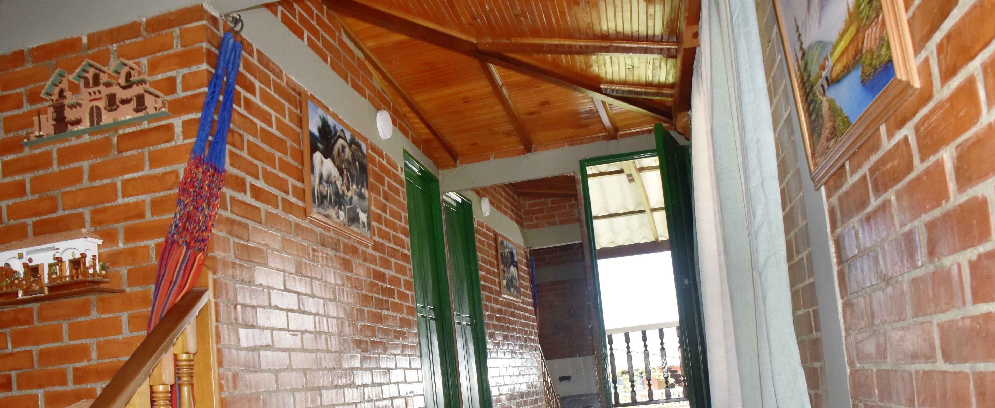 Une pièce aux murs en briques, au plafond orné de poutres en bois et à la porte verte.