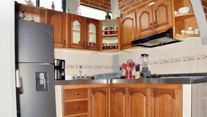 A kitchen with wooden cabinets, a refrigerator, a coffee maker, and a blender.