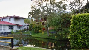 A building with a red roof and white walls, a small pond in front, and a yellow sign.