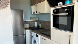 Una cocina moderna con un refrigerador de acero inoxidable, una lavadora integrada y un horno Brandt.