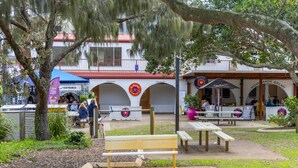 Uma área externa com mesas e bancos, um edifício com arcos e uma placa com 'El Pigface'.
