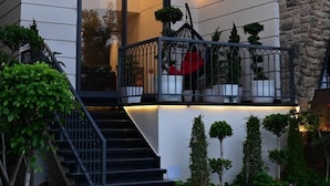 Una casa moderna con fachada de piedra, puerta de cristal y un pequeño balcón con plantas en macetas.