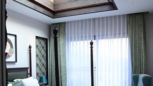 Una cama con dosel y cabecera de madera, cubrespr cama verdes y un tragaluz grande arriba.