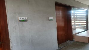 A hallway with two doors labeled 203 and 202, a bench, and a window with blinds.