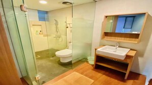 A modern bathroom with a glass shower enclosure, a white toilet, and a wooden vanity with a sink.