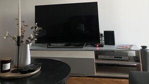 Un salón con televisor de pantalla plana, un reloj y cuadros en la pared.