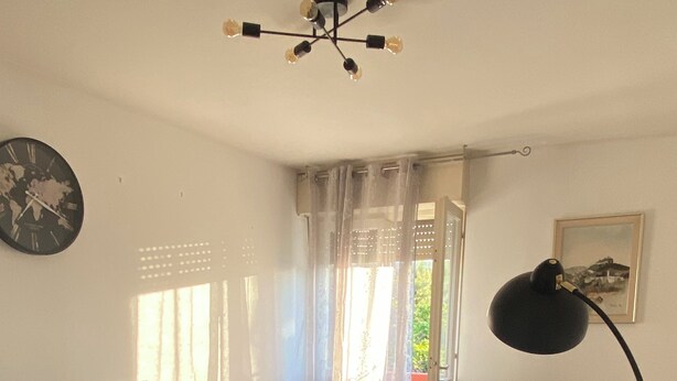 Una sala moderna con un sofá grande de color gris, un televisor de pantalla plana, una mesa de centro y una lámpara de pie.