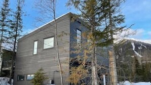 A modern two-story building with large windows, surrounded by snow-covered ground and trees.