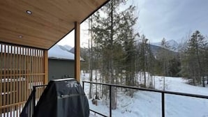 A covered outdoor area with a view of a snowy landscape and trees.