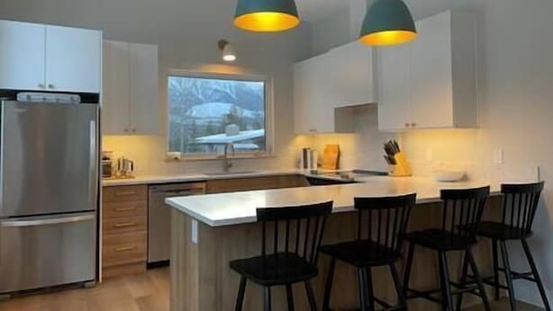 A modern kitchen with a central island, stainless steel appliances, and pendant lighting.
