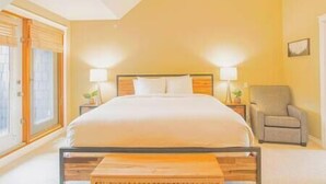 Een hotelkamer met een bed, nachtlampjes, een stoel en een raam.