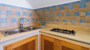 A kitchen with a double sink, a gas stove, wooden cabinets, and a tiled backsplash. - Corte dei Mesci - U Farraru - Historic Center Specchia (Specchia)