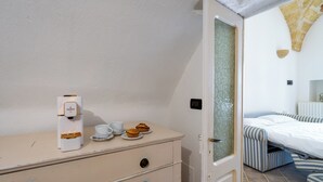 A room with a bed, a bedside table with a coffee machine, cups, and pastries. - Corte dei Mesci - U Farraru - Historic Center Specchia (Specchia)