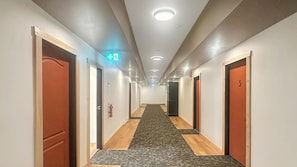 A hotel hallway with wooden floors, white walls, and doors numbered 5 and 6.