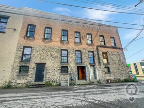 Un edificio de varios pisos con fachada de piedra, múltiples ventanas y una puerta.