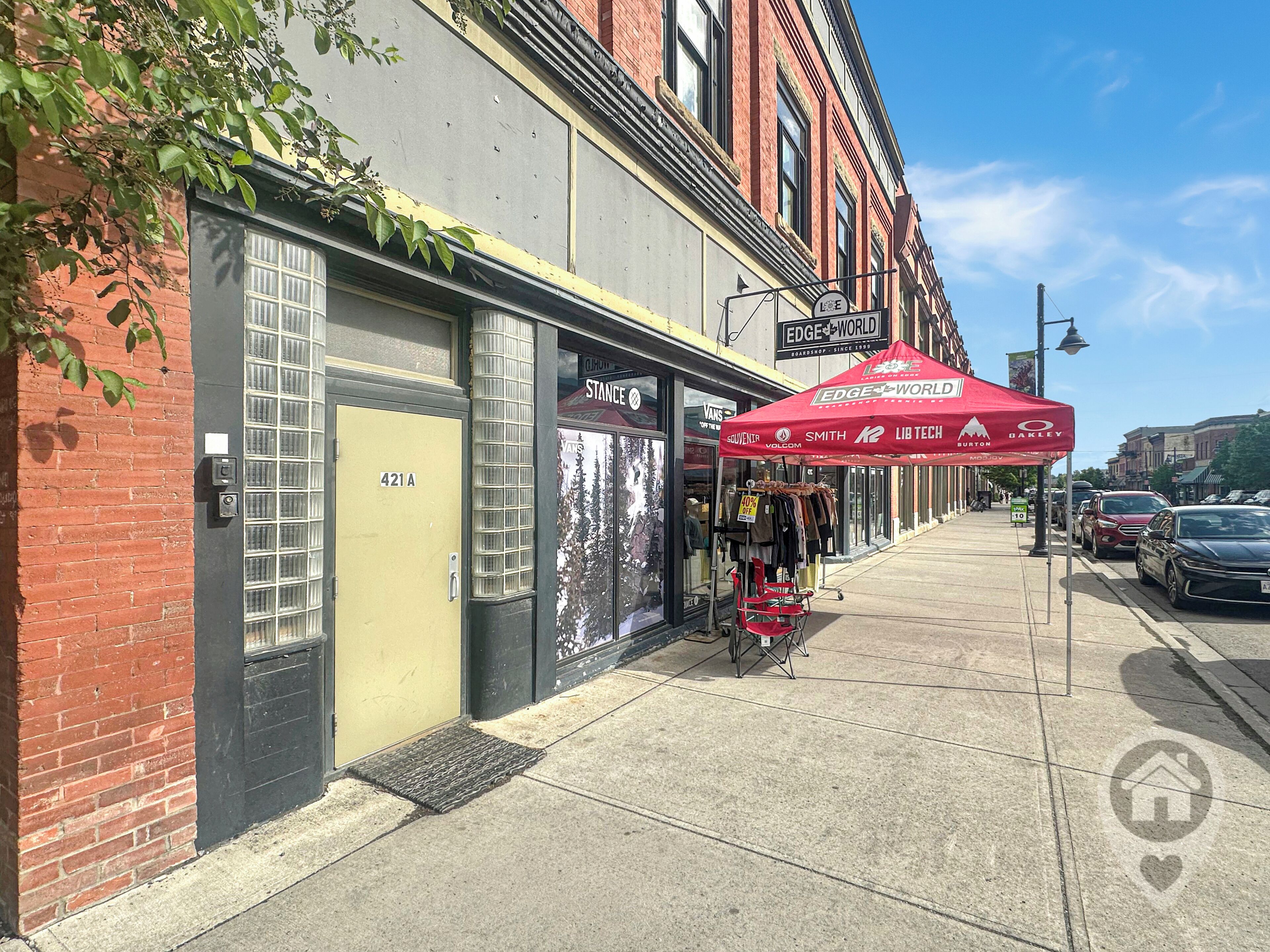 A street with a row of buildings, a red canopy, and a parked car.