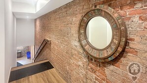 Eine Treppe mit hölzernem Geländer, einer Backsteinmauer und einem runden Spiegel.