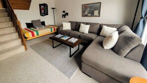 A living room with a sofa, a coffee table, and a staircase.