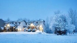 A residential building with multiple windows and a snow-covered landscape.