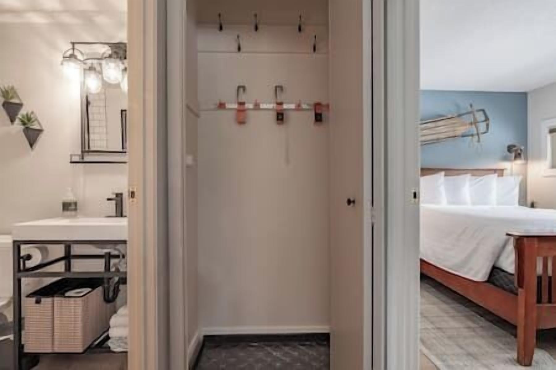 A bathroom with a shower, a sink, and a mirror. There is a towel rack above the shower and a towel hanging on it. The bathroom has a white wall and a window.