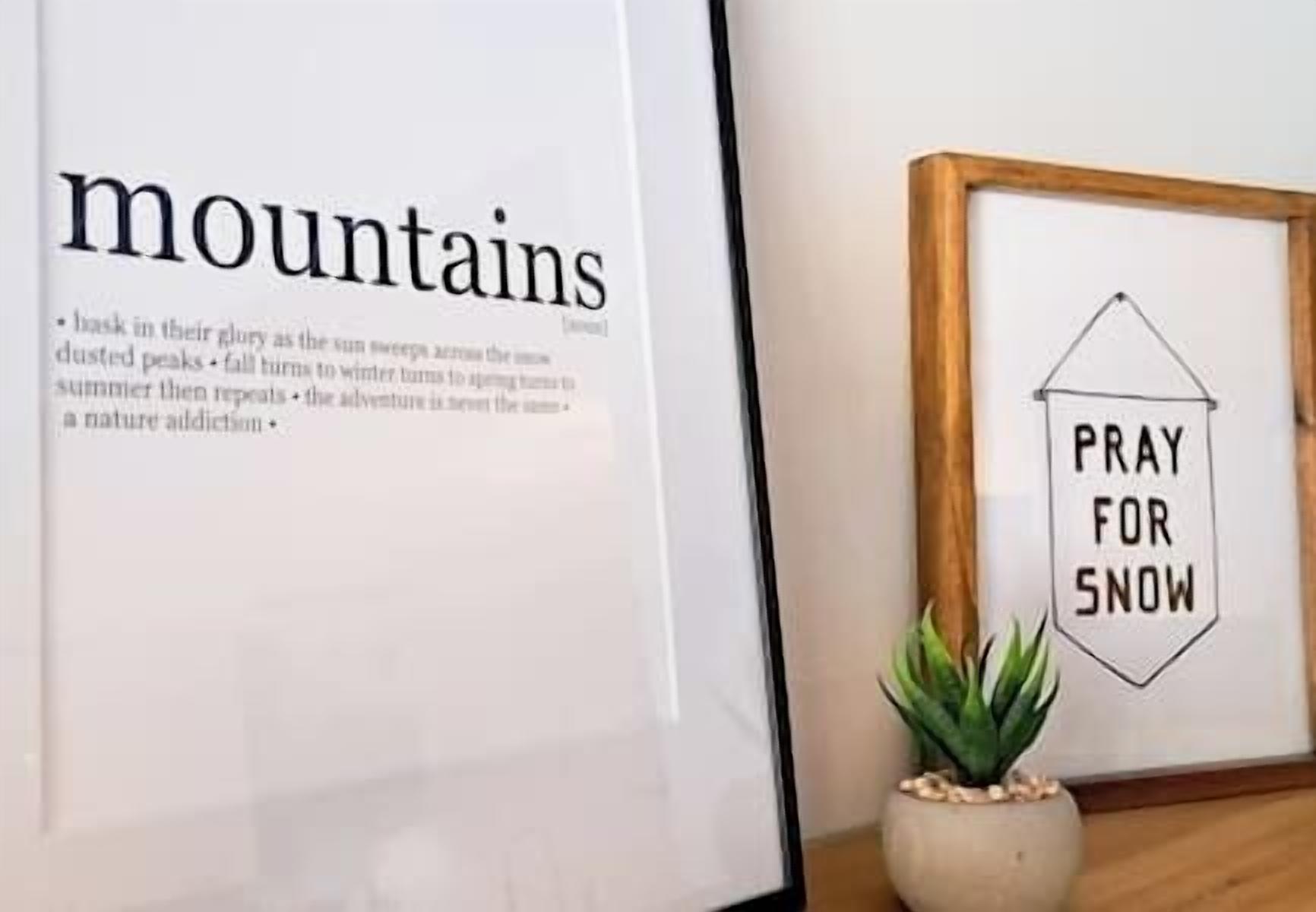 A framed text about mountains and a sign that says "PRAY FOR SNOW".