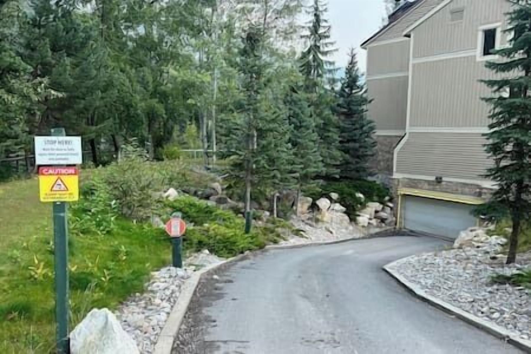 Una entrada de vehículos residencial con una señal de stop, una señal de precaución y una casa con garaje.