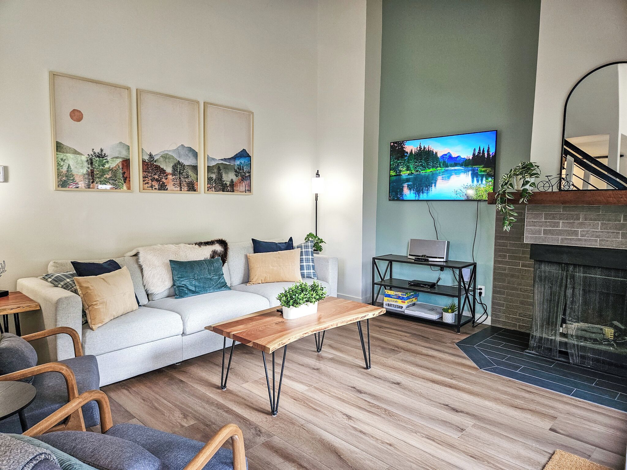 A modern living room with a sofa, coffee table, and TV. There are framed pictures on the wall and a fireplace.