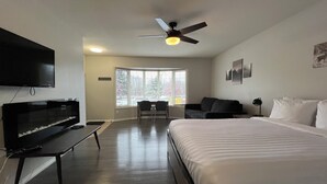 A hotel room with a bed, a desk, a television, and a ceiling fan. - 3 Bed Townhouse - Fireplace - Great Location (Fernie)