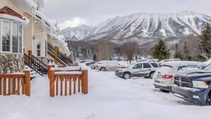 A hotel with a stone facade, a wooden staircase, and a view of snow-covered mountains. - 3 BDRM Condo - Superb Location - Parking (Fernie)