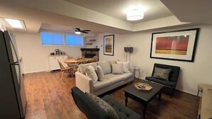A living room with a sofa, a coffee table, and a dining area with a table and chairs. - 3 BDRM Condo - Superb Location - Parking (Fernie)