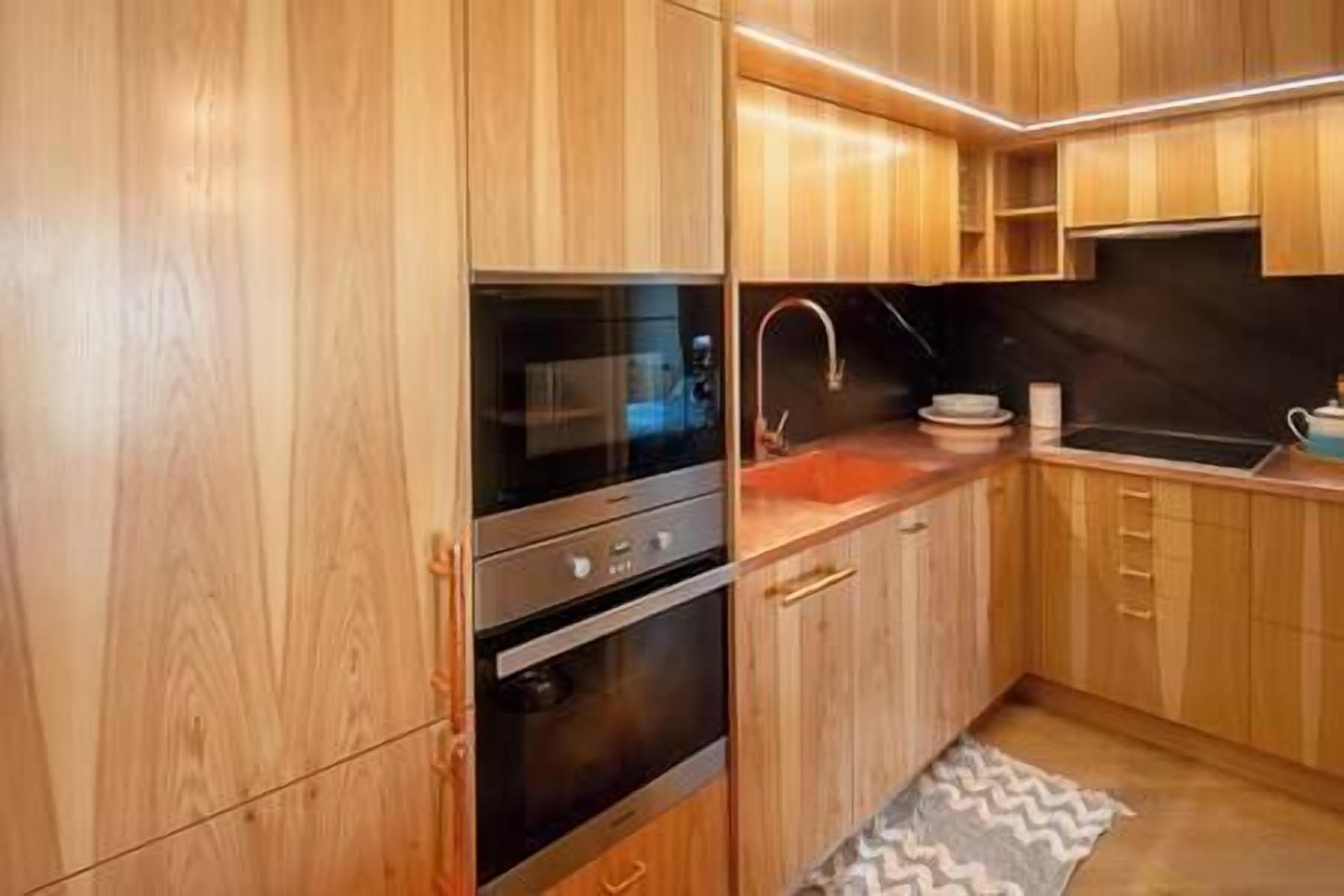 Une cuisine moderne avec des meubles en bois, des appareils en acier inoxydable et un plan de travail en granit.