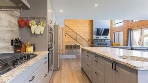 A modern kitchen with a central island, wooden cabinets, and a stainless steel range hood.
