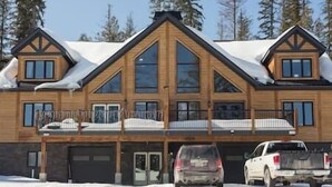 A large, two-story log cabin with a garage and a covered porch.