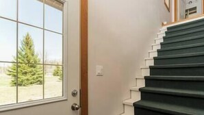 A staircase with a handrail and a door leading to a room with a window.