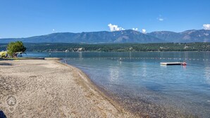 A lakeside view with a sandy beach, a small dock, and mountains in the background. - 3 BDRM / Lake Access / Year round Indoor pool (Windermere)