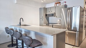 A modern kitchen with a large island, stainless steel appliances, and bar stools. - 3 BDRM / Lake Access / Year round Indoor pool (Windermere)