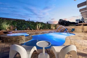 Une piscine avec un jacuzzi, des chaises longues et une table.