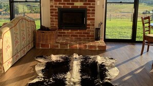 A living room with a brick fireplace, large windows, and a cowhide rug. - Big Sky Country Views  (Boyland)