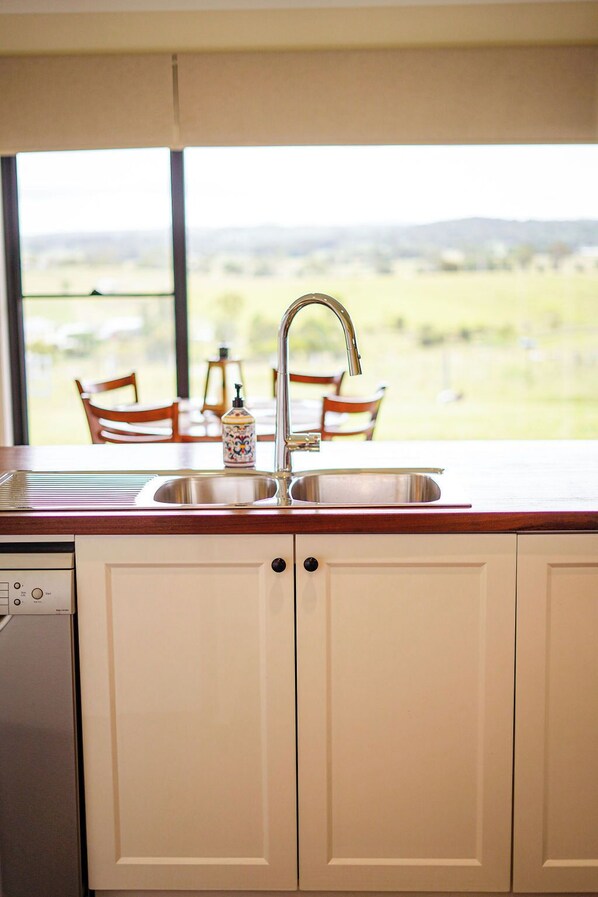 A kitchen with a sink, cabinets, and a window overlooking a landscape. - Big Sky Country Views (Boyland)
