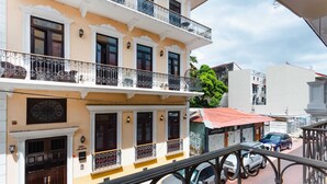 Un immeuble à plusieurs étages, doté de balcons, d’un auvent rouge et de voitures garées.
