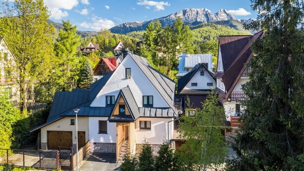 Ein Bergdorf mit traditionellen Häusern, blauem Himmel und einer Bergkulisse.